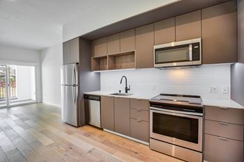 A modern kitchen with a stainless steel refrigerator, oven, and microwave.